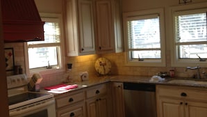 Una cocina con gabinetes blancos, una estufa y un reloj en la pared.