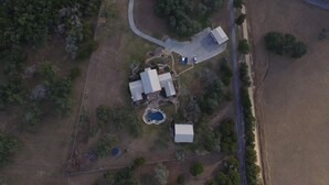 Vista aérea de una propiedad con una casa grande, una piscina y una cancha de tenis.