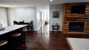 A spacious living area with a kitchen bar, a fireplace, and a dining area.