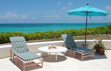 Oceanfront patio with 4 chaise lounges and round table with 4 chairs
