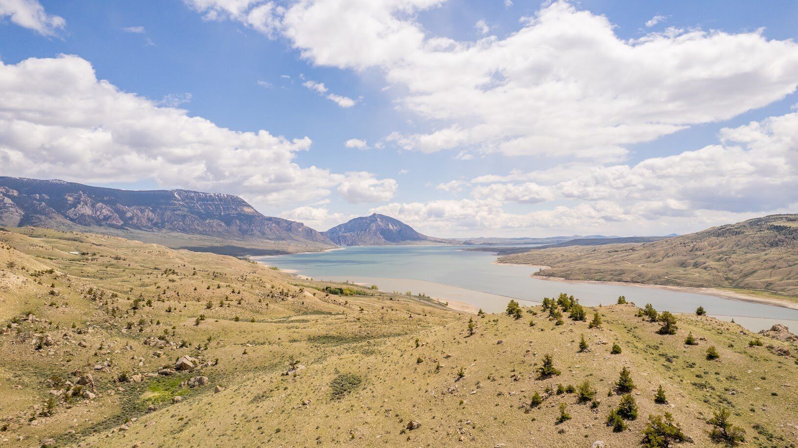 A panoramic view of a mountainous landscape with a lake and distant mountains.