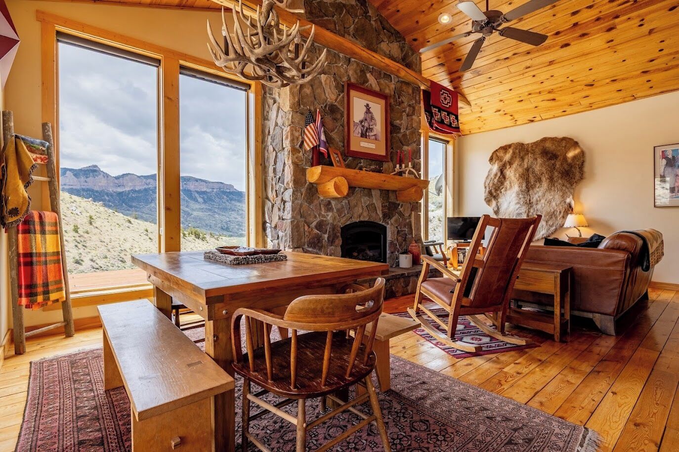 Un intérieur rustique avec une cheminée en pierre, des meubles en bois et une grande peau de bête servant de tapis.
