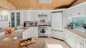 A modern kitchen with white cabinetry, a skylight, a stove, and a refrigerator. - Beautiful Oceanfront Home with Jacuzzi (Carpinteria)