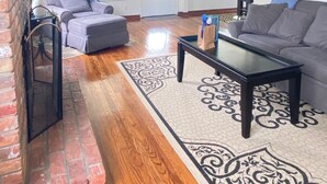 Ein Wohnzimmer mit Kamin, zwei Sofas, einem Couchtisch und einem gemusterten Teppich.