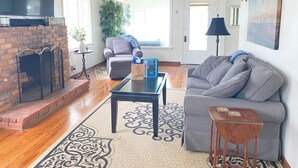 Ein Wohnzimmer mit Kamin, grauem Sofa, Couchtisch und Fernseher.