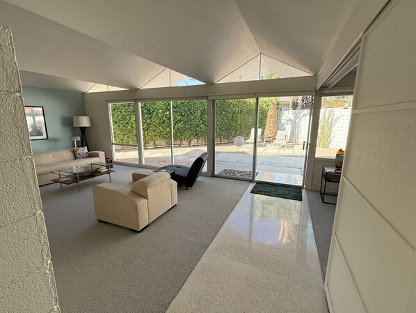 A spacious living room with a large sliding glass door leading to an outdoor patio area. - Palm Springs Mid - Century Modern (Palm Springs)
