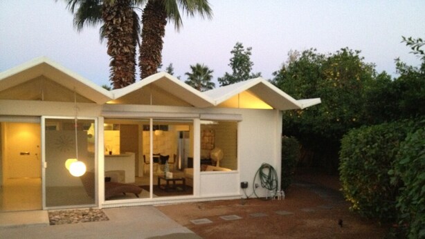 Een modern huis met een terras, grote ramen en een verzorgde tuin.