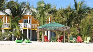 A beachside hotel with a thatched-roof gazebo, colorful chairs, and a pool area. - PRIVATE LUXURY, Beachfront Home, Hot Tub, Kayaks, Paddle Board, Cabana (Casuarina Point)