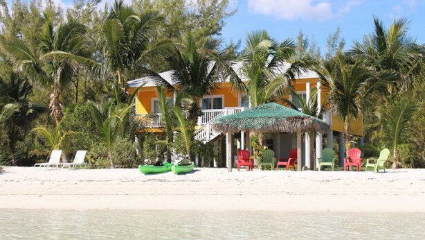 A beachside resort with a thatched-roof hut, colorful chairs, and a clear view of the ocean. - PRIVATE LUXURY, Beachfront Home, Hot Tub, Kayaks, Paddle Board, Cabana (Casuarina Point)