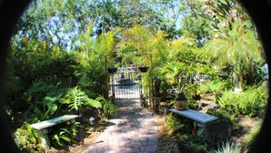 A garden pathway with a bench, potted plants, and a gate leading to a building. - "Your Own Private Resort" at 9 Oaks!            (New Smyrna Beach)