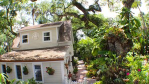 A two-story house with a porch, surrounded by lush greenery and trees. - "Your Own Private Resort" at 9 Oaks!            (New Smyrna Beach)