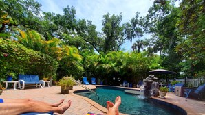 A pool area with lounge chairs and a small waterfall feature. - "Your Own Private Resort" at 9 Oaks!            (New Smyrna Beach)