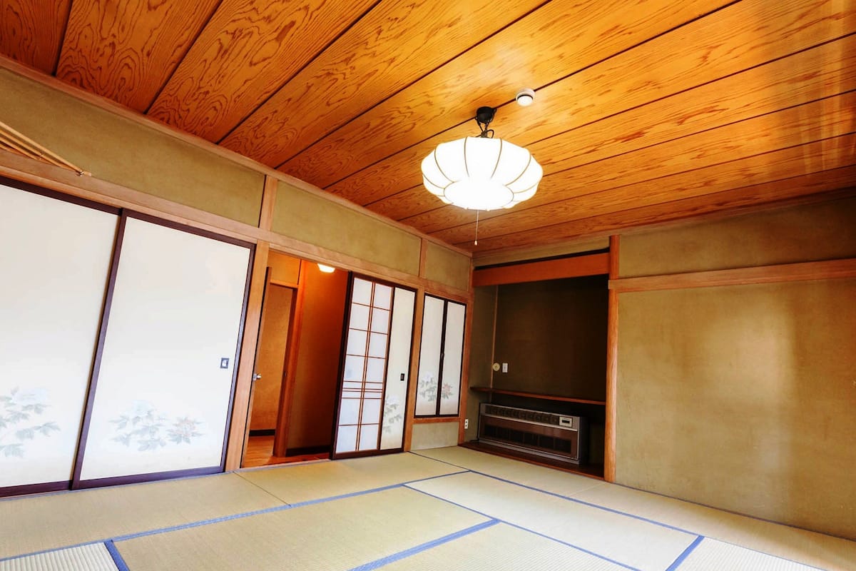 A traditional Japanese room with tatami flooring, sliding doors, and a ceiling fan.