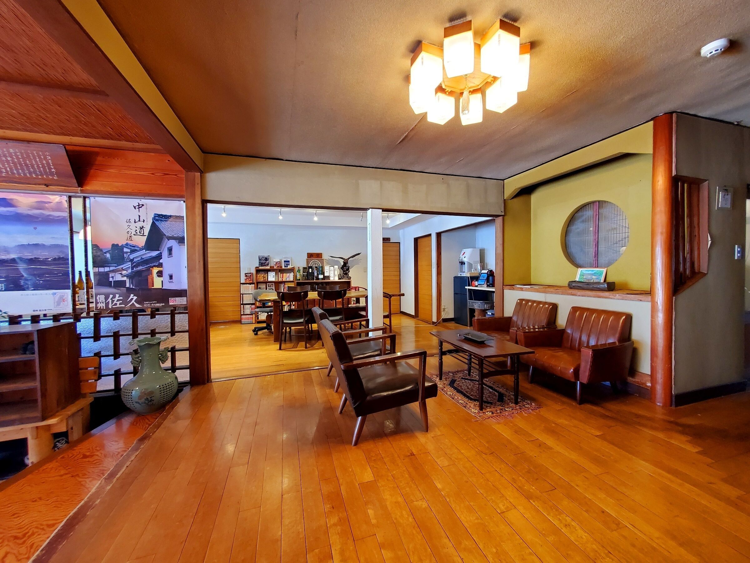 A spacious room with wooden flooring, a chandelier, and a seating area with chairs and a table.