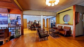 A spacious room with wooden flooring, a chandelier, and a seating area with chairs and a table.