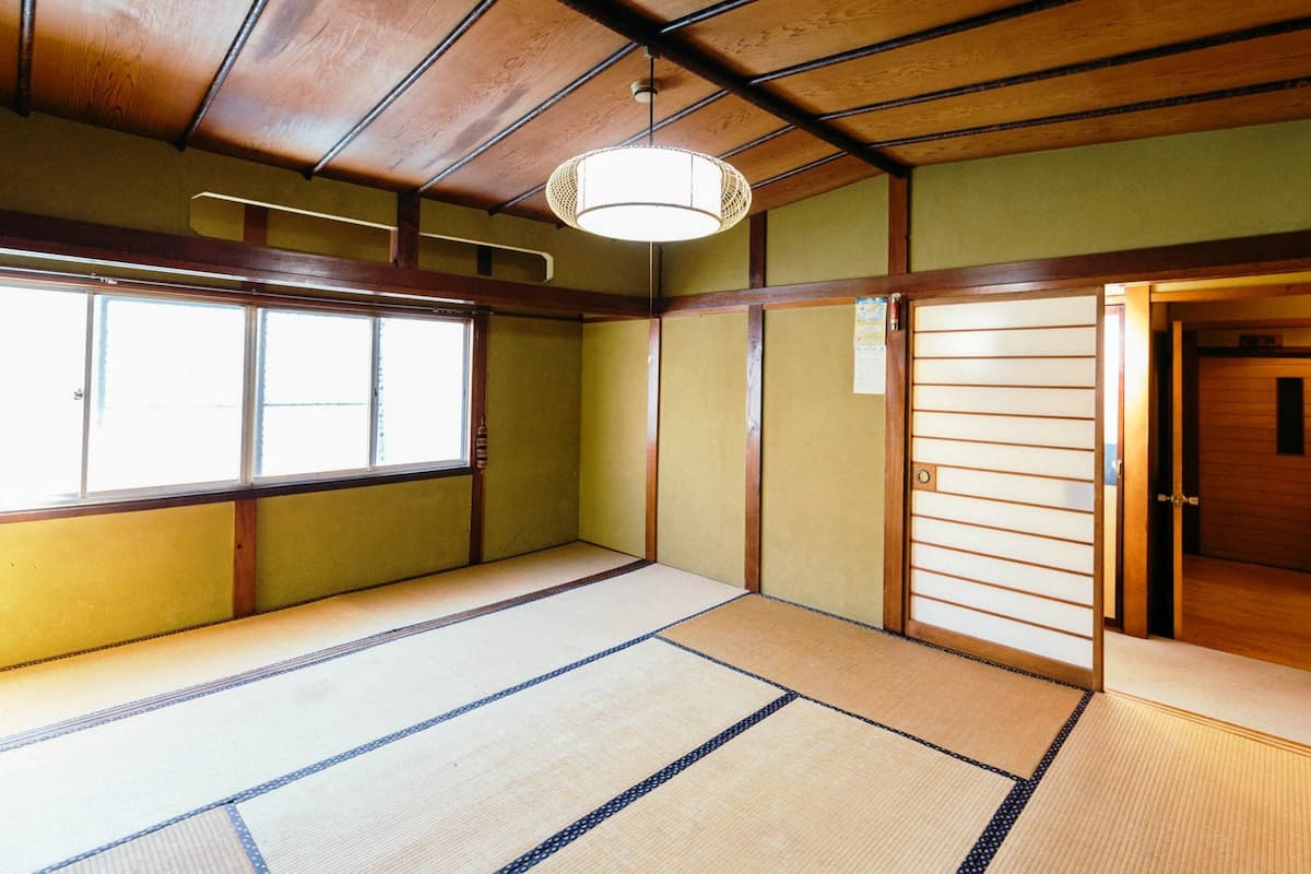 A traditional Japanese room with tatami flooring, a sliding door, and a window with a view.