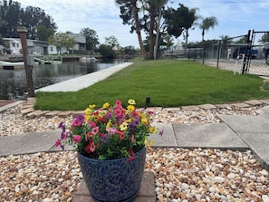 Une propriété située au bord de l’eau, avec une pelouse verdoyante, un canal et un pot de fleurs.