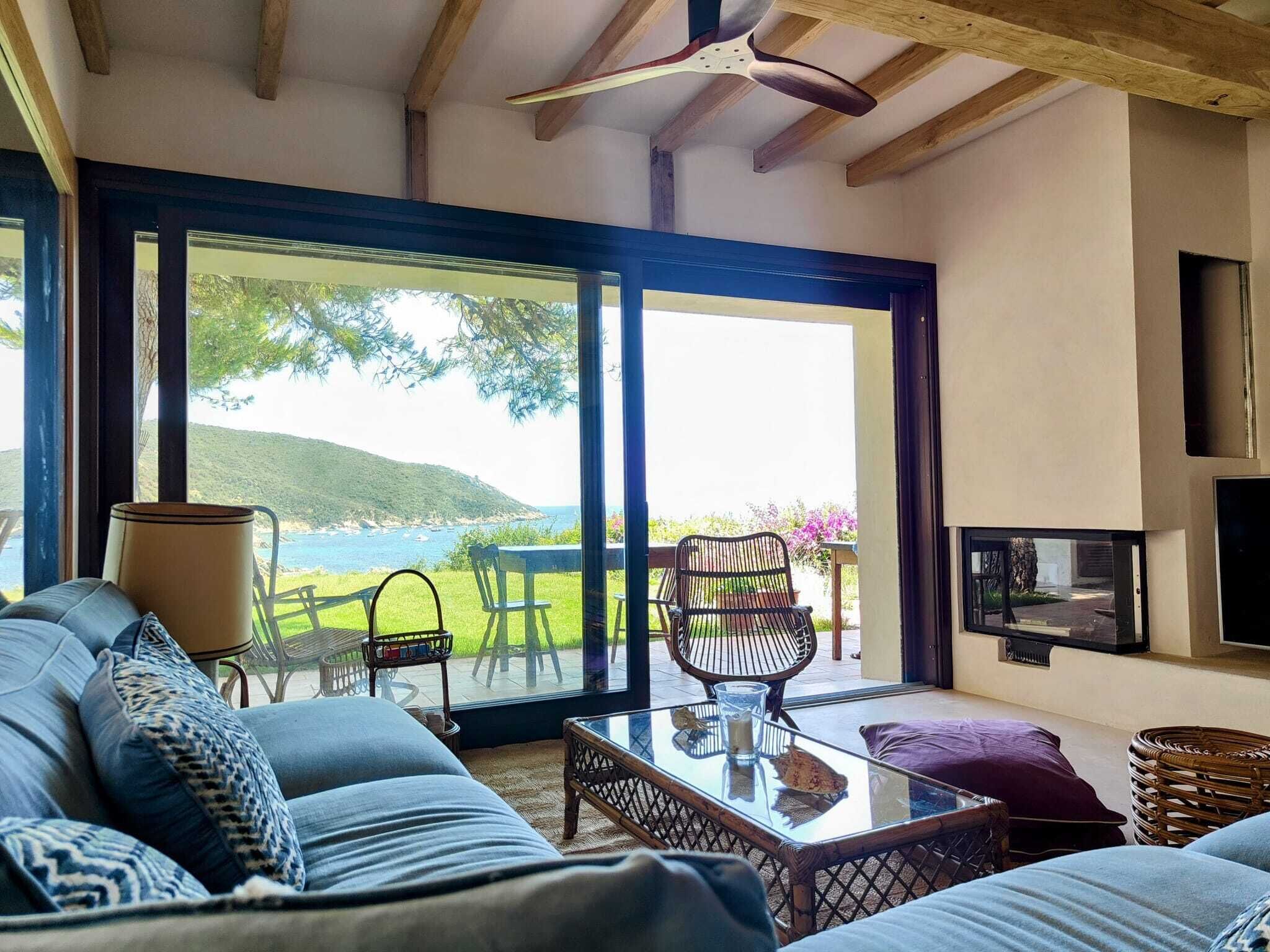A modern living room with a large sliding glass door leading to a balcony with a scenic view of hills and water.