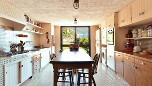 Een keuken met een centraal eiland, houten keukenkastjes en uitzicht op de omgeving.