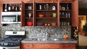 Una cocina con salpicadero de piedra, armarios de madera, estufa y lavamanos.