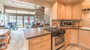 A modern kitchen with wooden cabinets, a gas stove, a microwave, and a large island with a kettle.