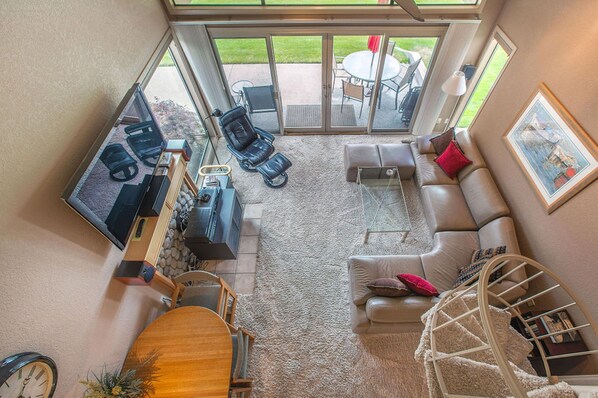 A spacious living area with a large TV, comfortable seating, a dining table, and a view of the outdoors.
