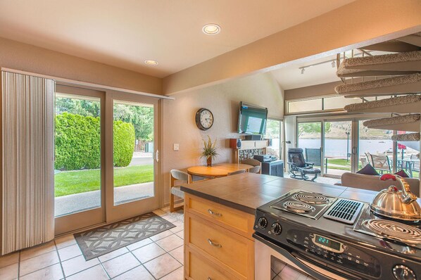 A kitchen with a stove, a dining area, and a view of the outdoors.