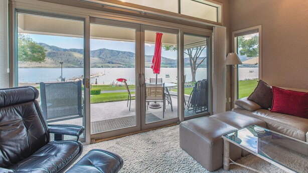 A spacious living room with a large sliding glass door leading to a patio area with outdoor furniture.