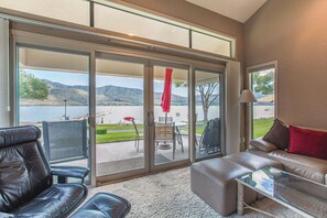 A spacious living room with a large sliding glass door leading to a patio area with outdoor furniture.