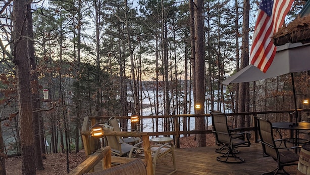 Eine Holzterrasse mit Sitzgelegenheiten und Blick auf einen Wald, sowie eine amerikanische Flagge.