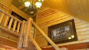 Eine Holztreppe mit einer Kandelaber und einem gerahmten Bild an der Wand.