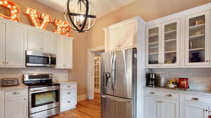 Une cuisine moderne avec des meubles blancs, des appareils en acier inoxydable et un lustre.