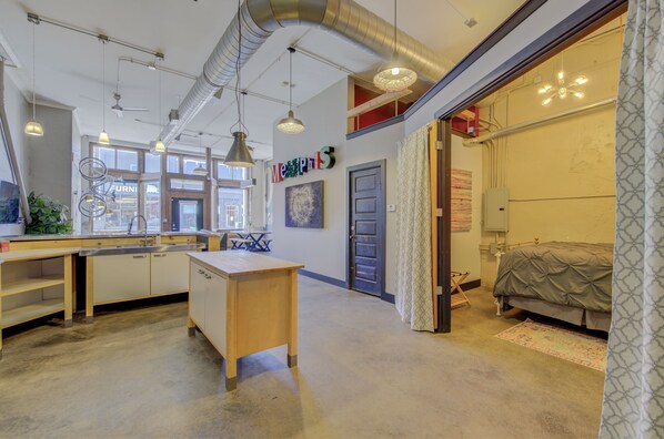 A spacious kitchen with modern appliances, a dining area with a table and chairs, and a bedroom with a bed and a window.