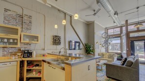 Cocina compacta con una isla central, armarios empotrados y un comedor con sofá y mesa de centro.