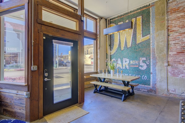 A wooden door with a glass panel, a picnic table with benches, and a mural on the wall.