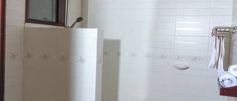 Une salle de bain comprenant des toilettes, un lavabo, une douche et un porte-serviettes.