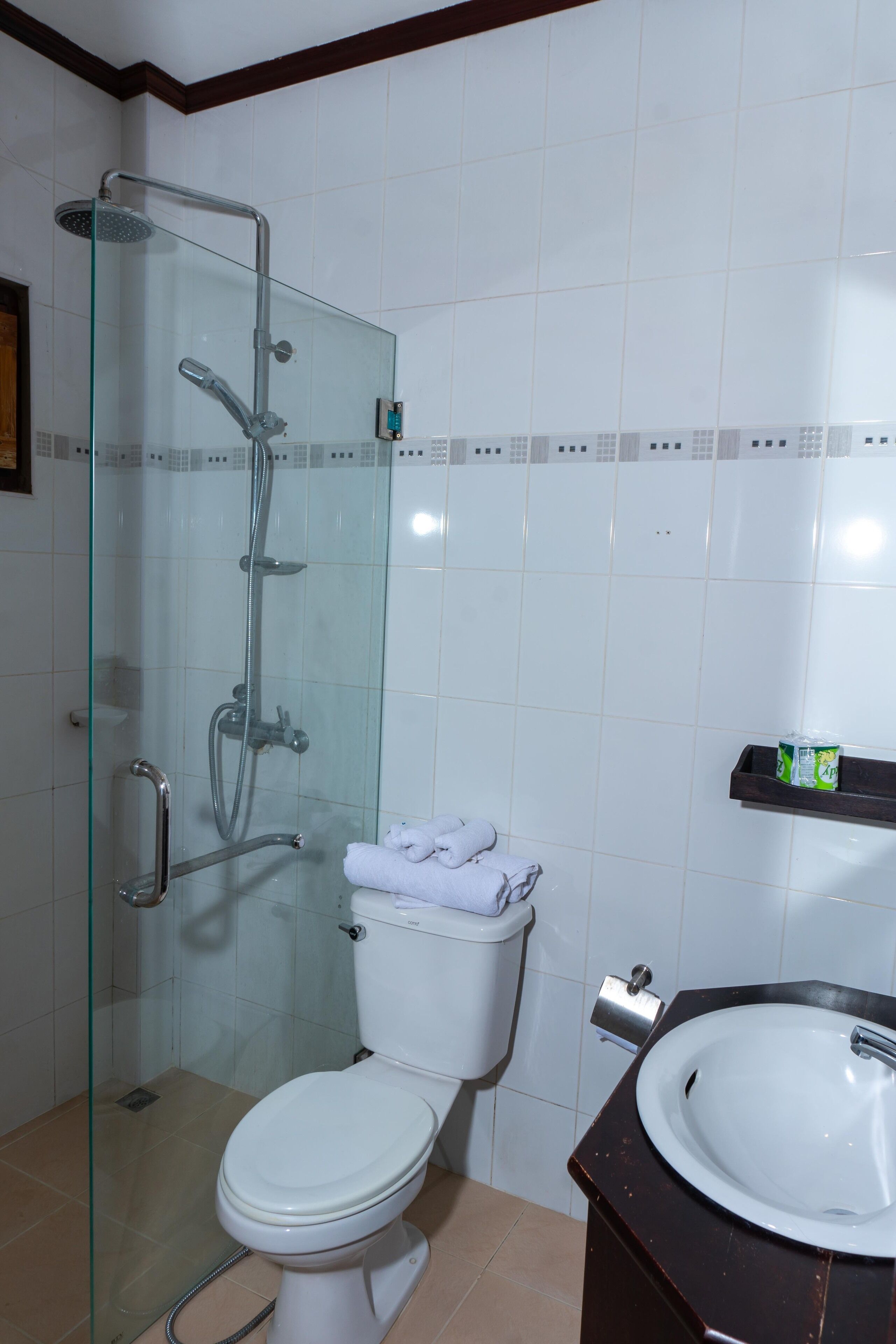 A bathroom with a glass-enclosed shower, a toilet, and a sink.