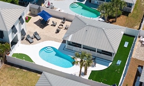 A residential property with two swimming pools, a covered patio, and a fenced yard.