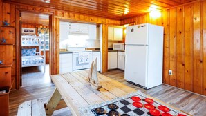 A wooden cabin interior with a kitchen, dining area, and a bed. - Beach Cottage Heart of Ocean Drive Sleeps 14 (North Myrtle Beach)
