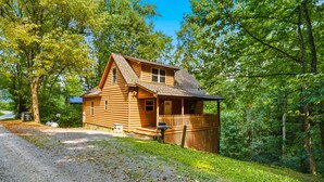 Une cabane en bois avec un porche, entourée d’arbres.