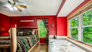 Een kamer met een bed, een groot raam, een badkuip en een plafondventilator.