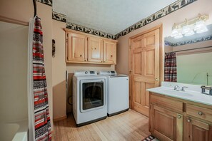 A laundry room with two washing machines, wooden cabinets, and a sink. - Honeymoon, private settings, 10 min from main street, family fun, fishing pond (Sevierville)