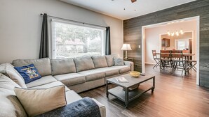 Uma sala de estar moderna com sofá, mesa de centro e área de jantar com mesa e cadeiras.