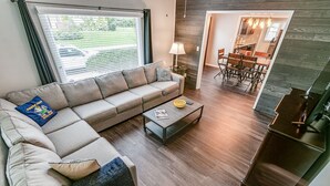 Uma sala moderna com um sofá seccional, uma mesa de centro e um espaço de jantar com mesa e cadeiras.
