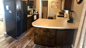 A kitchen with a black refrigerator, wooden cabinets, a granite countertop, and a microwave. - Cozy, 3 bedroom home- ideal for couples or families (Forks)