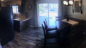 A kitchen with a wooden floor, a dining table with chairs, a refrigerator, and a window with curtains. - Cozy, 3 bedroom home- ideal for couples or families (Forks)