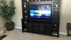 A dark wooden entertainment center with a flat-screen TV displaying a home screen with app and channel options. - Cozy, 3 bedroom home- ideal for couples or families (Forks)