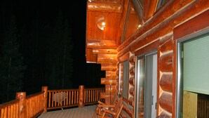 Eine Holzhütte mit einer Terrasse, einer Glastür und einem Fenster.