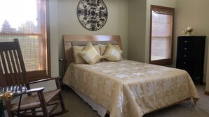 Ein Schlafzimmer mit einem Bett, einem Sessel, einer Kommode und einer Wanddekoration.