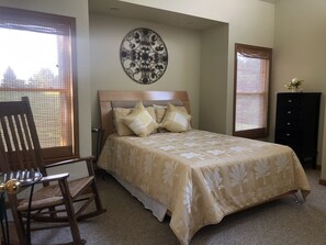 Een slaapkamer met een bed, een stoel, een dressoir en een decoratief wandobject.